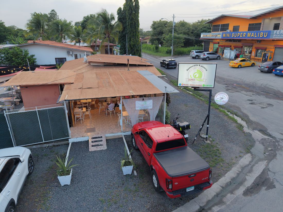 Vista aérea del frente de Mambo Italiano con la terraza techada y el parqueo sobre la calle